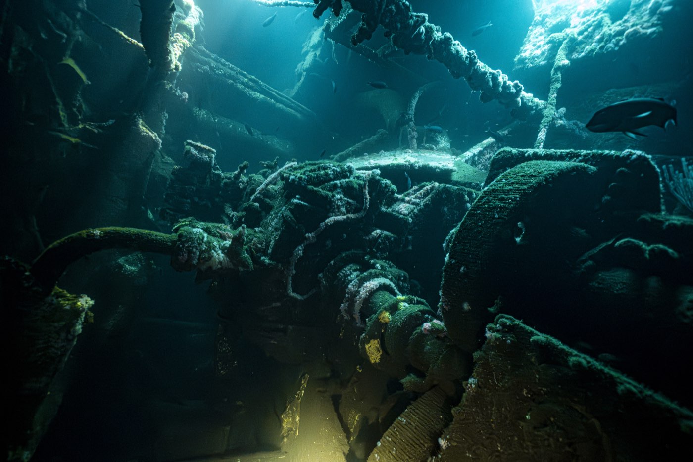 Inside the Yukon's engine room: pipework and machinery, stripped of oil before sinking, under a diver's light