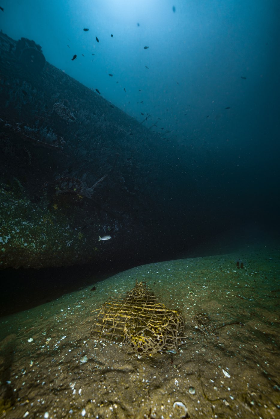 A lobster trap on the sand under the Yukon's bow: the site is fished, and trap lines run around the hull in season